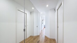 Un couloir aux murs recouverts de miroirs et au plancher en bois, qui mène à une porte au fond.