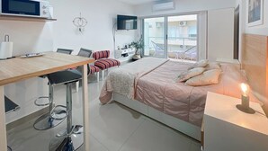 Une chambre à coucher moderne avec un lit, une table de chevet et un espace bureau.