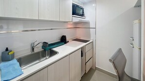 Une cuisine de taille réduite, équipée d’un évier, d’un four à micro-ondes et d’une chaise.
