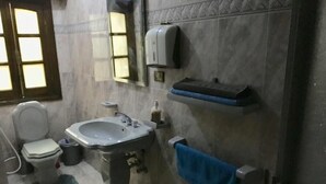 A bathroom with a toilet, sink, and towel rack. - One Bedroom Apartment City Views Local to Airport (Cairo)