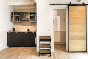 A kitchen with dark cabinetry, a wooden countertop, and a sliding door leading to a bathroom.