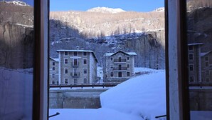 A snow-covered mountain landscape with buildings in the background. - Grand Hotel Ceresole Reale Bill Apartment (Ceresole Reale)