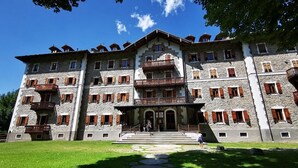 A multi-story stone building with balconies and a central entrance. - Grand Hotel Ceresole Reale Bill Apartment (Ceresole Reale)