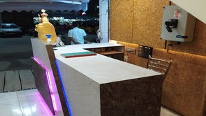 A reception desk with a marble counter, a decorative golden statue, and a wall-mounted electrical box. - JR Grande (Kilvelur)