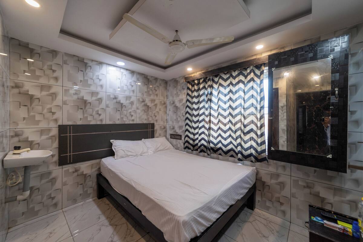 A modern bedroom with a bed, a built-in sink, and a large mirror.