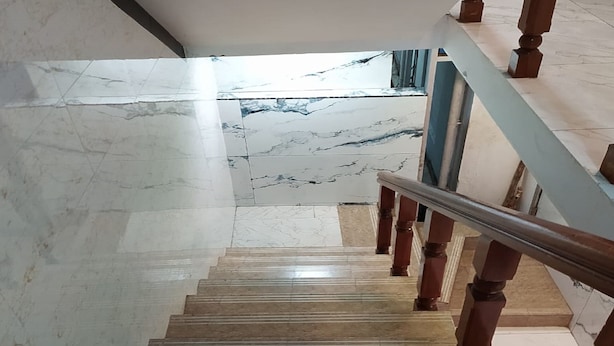 A marble staircase with wooden balusters and a metal handrail, leading to a landing with a view of a body of water. - JR Grande (Kilvelur)