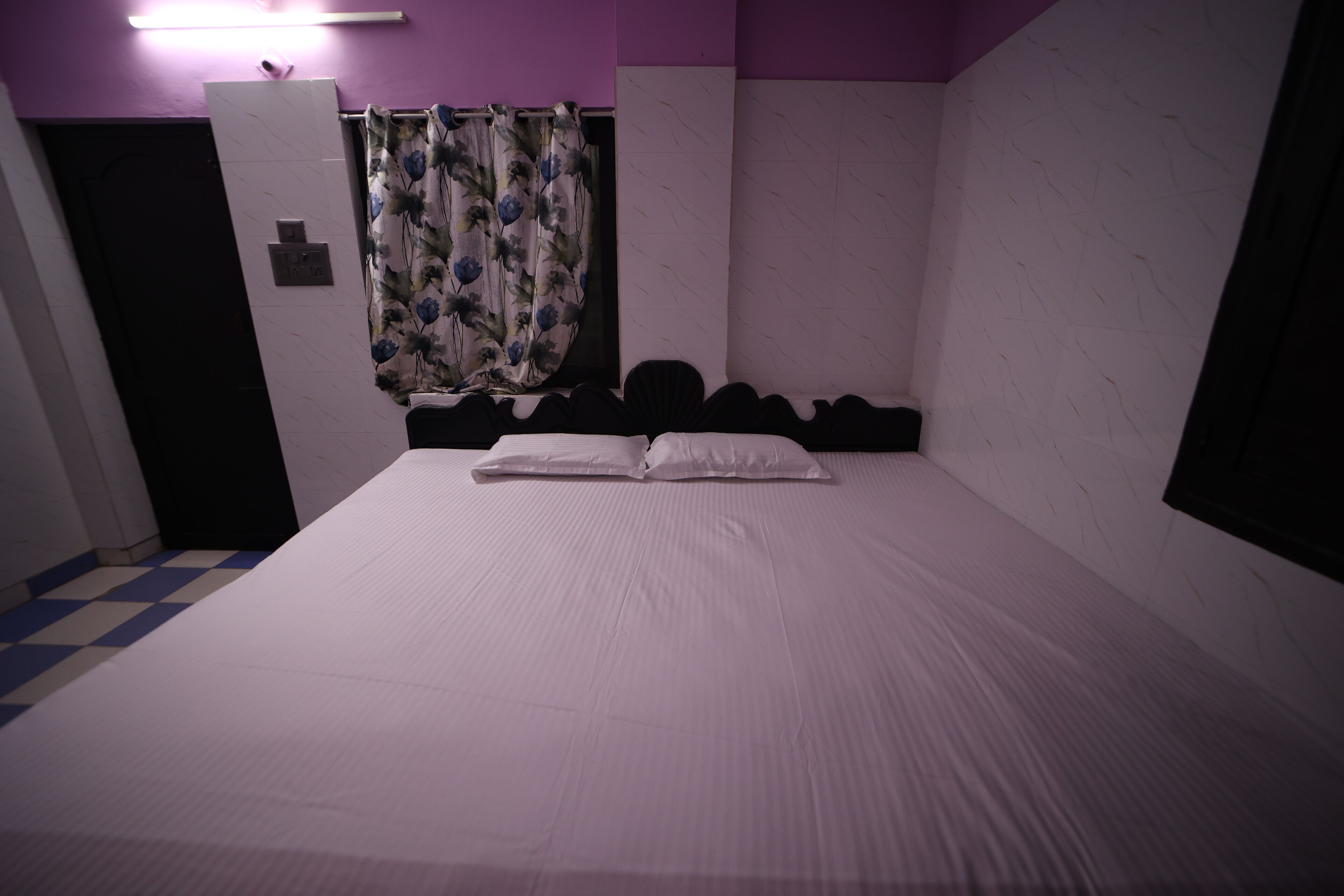 Quarto com cama, chuveiro e porta do banheiro.