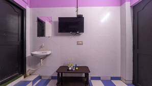 A bathroom with a sink, mirror, and a television mounted on the wall. - JR Grande (Kilvelur)