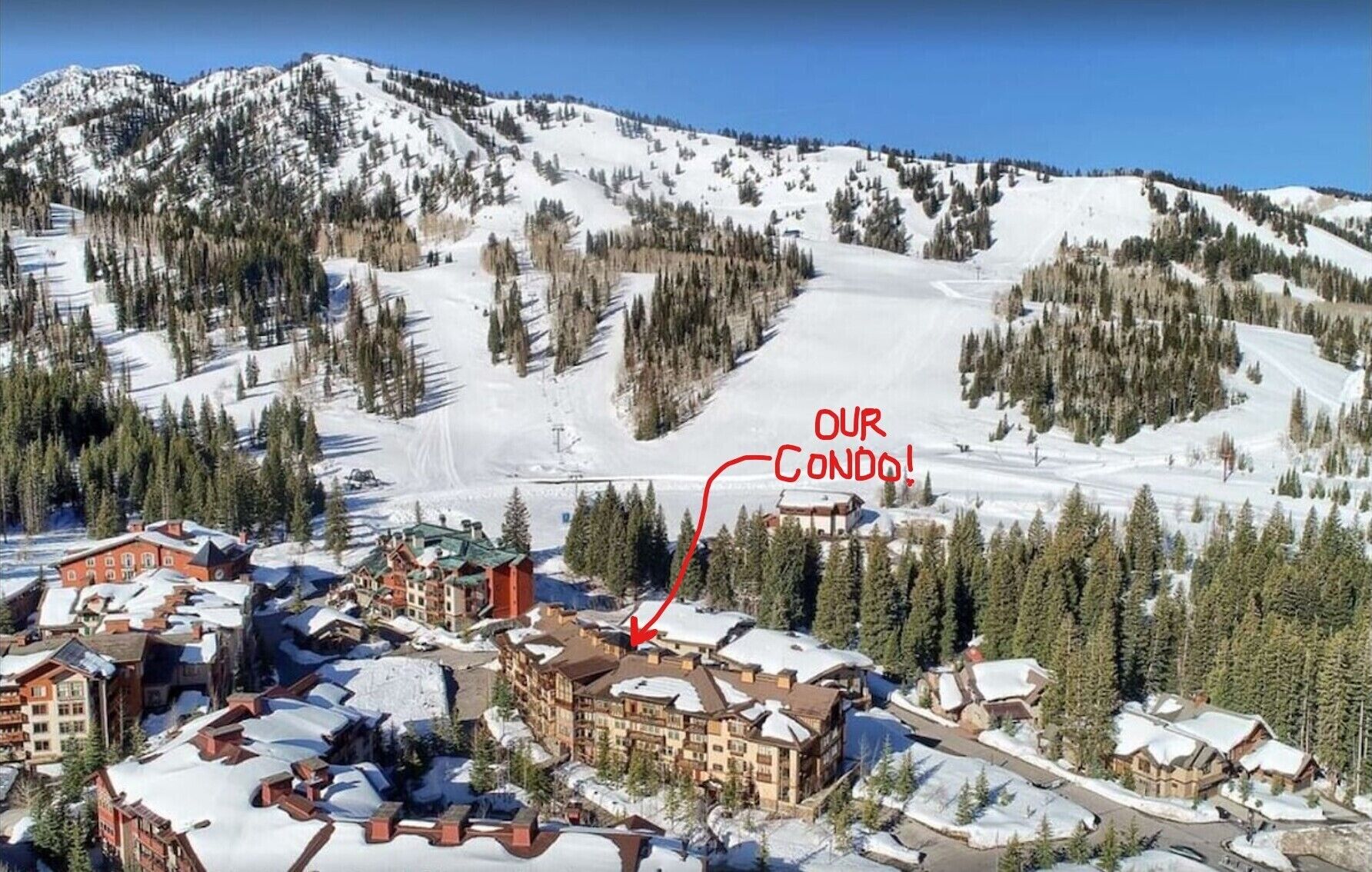 Pueblo nevado en la montaña con un cartel que dice 'OUR CONDO!', indicando una propiedad específica.