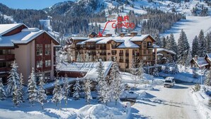 Ein schneebedecktes Skigebiet mit einem großen Chalet und mehreren Gebäuden, umgeben von Bäumen und einer Skipiste.