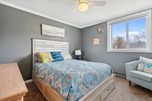 A bedroom with a bed, a nightstand, a dresser, a window, and a ceiling fan. - Beach Vibes on Lake Michigan (South Haven)