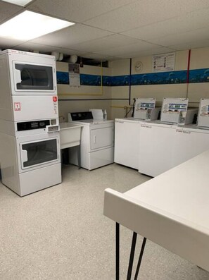 A laboratory with white cabinets, a large white machine, and a desk with a computer.