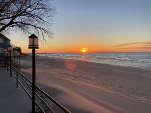 A beach with a sunset, a lamppost, and a building with a balcony. - Beach and pool are right there to enjoy! (South Haven)