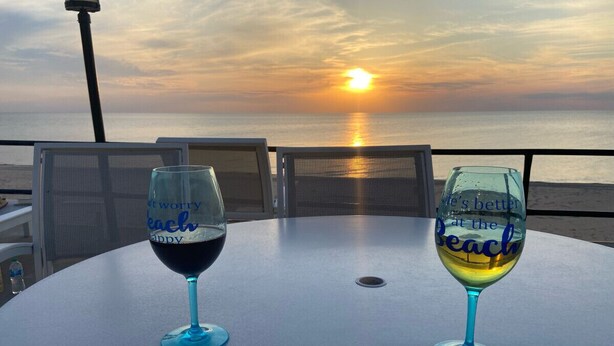 Two wine glasses on a table with a sunset view. - Beach and pool are right there to enjoy! (South Haven)