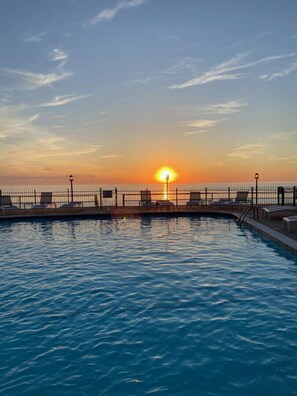 A swimming pool with a sunset view, a fence, and lounge chairs. - Beach and pool are right there to enjoy! (South Haven)