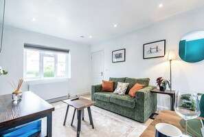 A living room with a green sofa, a coffee table, a lamp, and a framed picture on the wall.