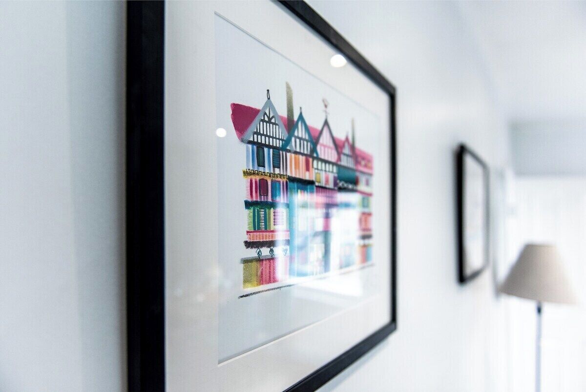 A framed artwork of colorful houses on a wall.
