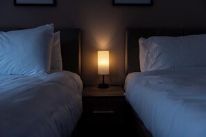 Habitació d'hotel amb dos llits, una tauleta de nit amb una làmpada i quadres a la paret.