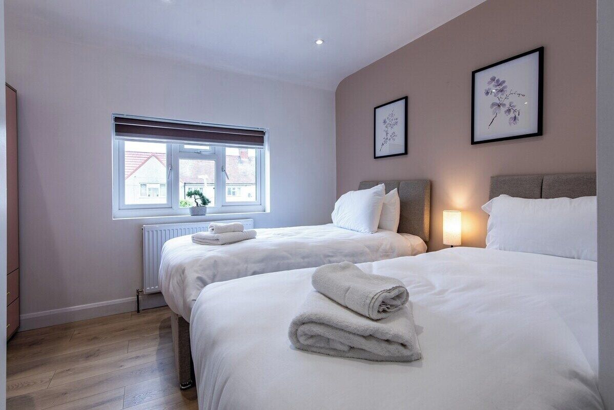 Une chambre d’hôtel avec deux lits, une fenêtre donnant sur un paysage agréable et un radiateur.
