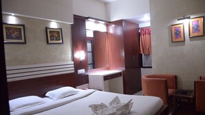 Una habitación de hotel con cama, escritorio, silla y espejo.