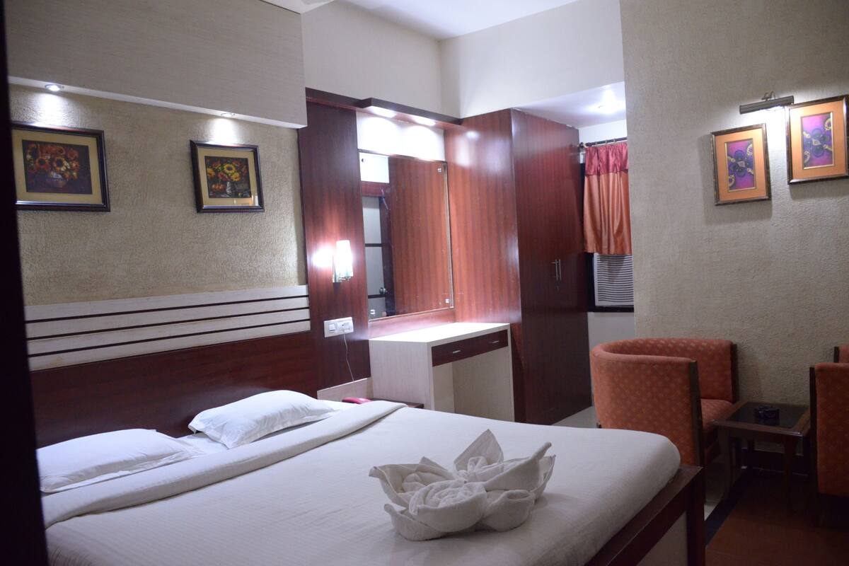 A hotel room with a bed, a desk, a chair, and a mirror.