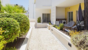 Une cour avec un sol carrelé, un petit espace aménagé pour s’asseoir et un bâtiment doté d’un balcon.