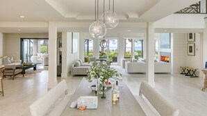 A spacious living room with a central dining table, sofas, and a fireplace. - South Beach Serenity by AvantStay | Private Pool + Beachfront (Hilton Head Island)