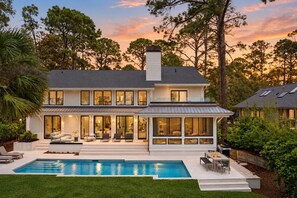 A two-story house with a swimming pool, large windows, and a balcony.