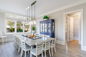 A dining area with a large table, white chairs, and a blue cabinet.
