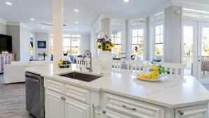 A spacious kitchen with a large island, white cabinetry, and a view to the outdoor deck.