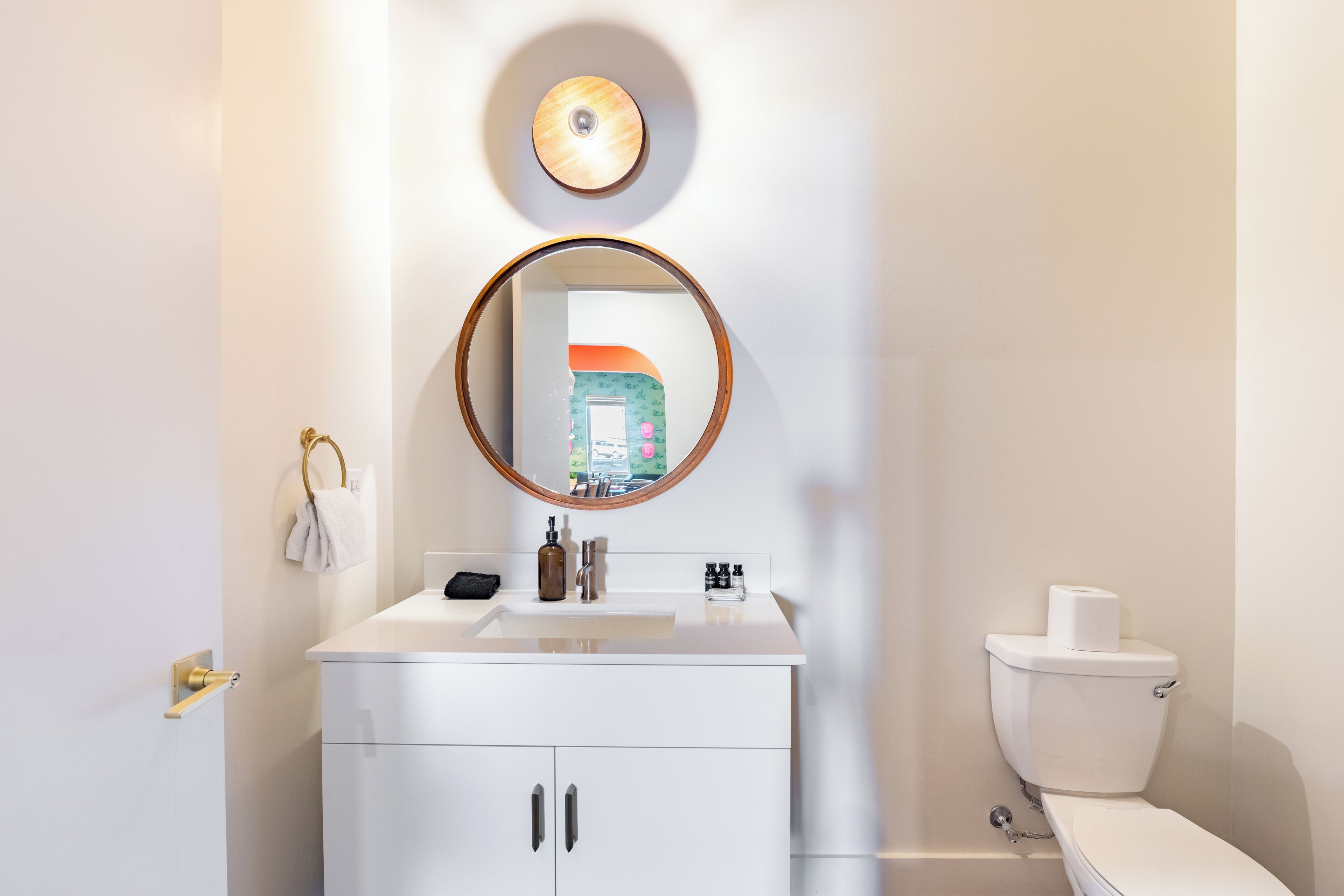 A bathroom with a white sink, a mirror, a toilet, and a towel rack.
