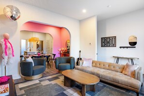 A modern living room with a sofa, two armchairs, a coffee table, and a dining area with a table and chairs. - The Last Rodeo | Bachelorette Retreat | Sleeps 24 | 5 Mins to Broadway (Nashville)