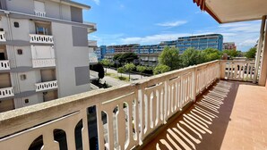 Un balcon doté d’une balustrade blanche, donnant sur un quartier résidentiel avec des immeubles à plusieurs étages.