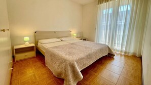 Une chambre à coucher avec un lit, des lampes de chevet, une table de chevet et une fenêtre avec des rideaux.