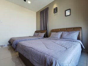Habitación de hotel con dos camas, una lámpara en el techo y dos cuadros colgados en la pared.