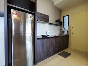 Una cocina moderna con refrigerador de acero inoxidable, armarios de madera oscura y salpicadero de azulejos.