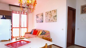 A dining area with a white table, wooden chairs, and a red tray. - Apartment in Caorle near Sandy Beaches (Caorle (VE))