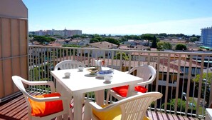 A balcony with a white table and chairs, a view of the cityscape, and a clear sky. - Apartment in Caorle near Sandy Beaches (Caorle (VE))