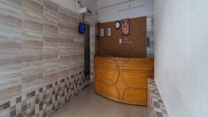 Un área de recepción con un mostrador de madera, un ventilador de techo y un televisor montado en la pared.