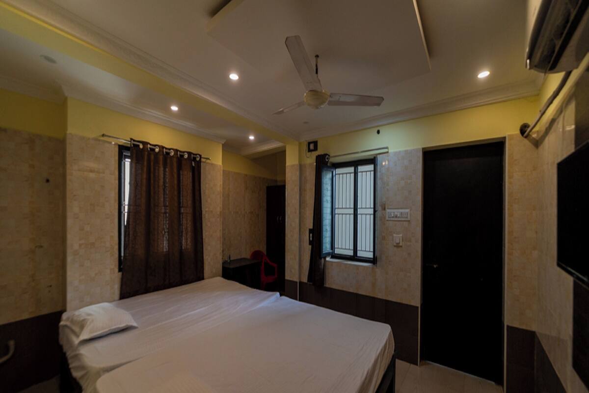 A bedroom with a bed, a ceiling fan, a window, and a door.
