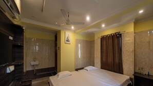 Una habitación de hotel con una cama grande, una mesita de noche, un espejo y un ventilador de techo.