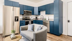 Une cuisine de taille réduite avec des meubles bleus, un four à micro-ondes et un lave-vaisselle.