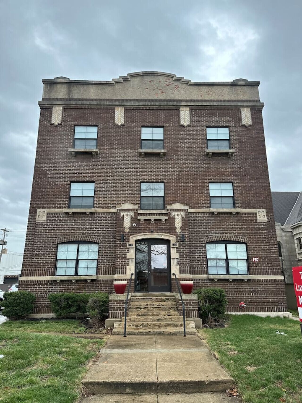 A multi-story brick building with a central entrance, large windows, and a symmetrical facade.