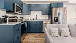 A modern kitchen with blue cabinets, stainless steel appliances, and a built-in dishwasher. - Central Loft with Pool Table! Pet-friendly Haven! (Columbus)