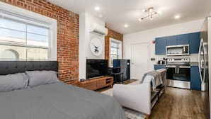 A modern room with a bed, a TV, a fireplace, and a kitchenette. - Central Loft with Pool Table! Pet-friendly Haven! (Columbus)