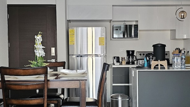 Una cocina moderna con una isla central, sillas de madera oscura y un tapete blanco.