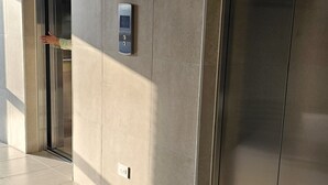 Un ascensor con panel de control y puerta metálica en un edificio moderno.