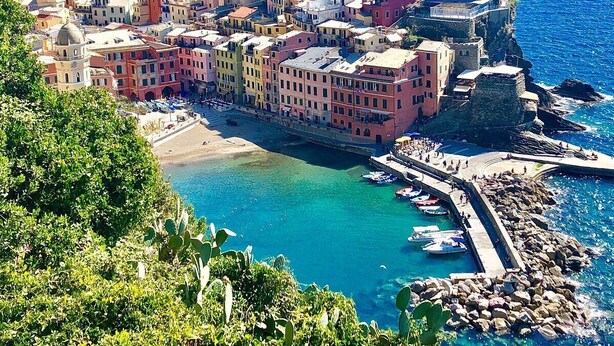 A coastal town with colorful buildings, a beach, and boats docked at the harbor. - Per una vacanza meravigliosa. (La Spezia)
