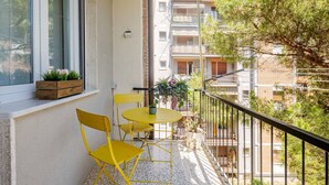 A balcony with yellow chairs and a small table, overlooking a residential area with multiple buildings. - Per una vacanza meravigliosa. (La Spezia)