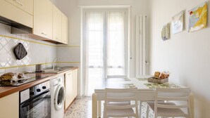 A compact kitchen with a washing machine, a sink, and a dining area with a table and chairs. - Per una vacanza meravigliosa. (La Spezia)